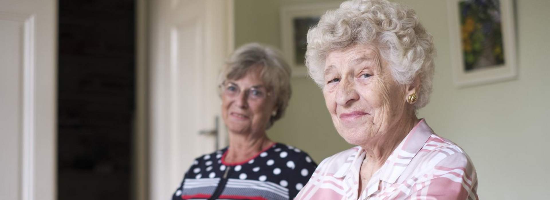 Pflege bei der AWO Kiel. Das Symbolbild zeigt zwei ältere Damen, die selbstbewusst in die Kamera schauen.